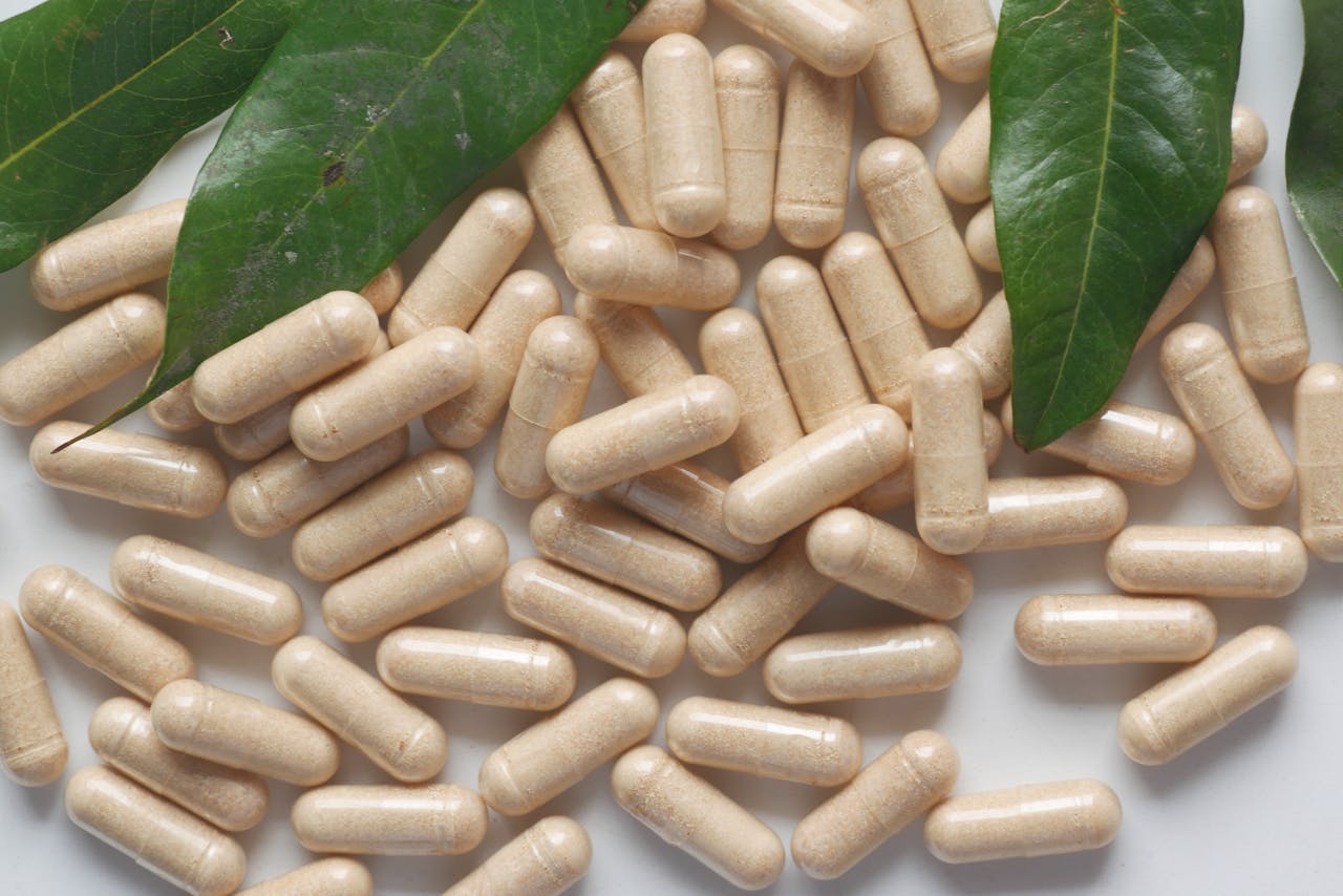 About Organic medicine capsules with fresh green leaves on a white background.