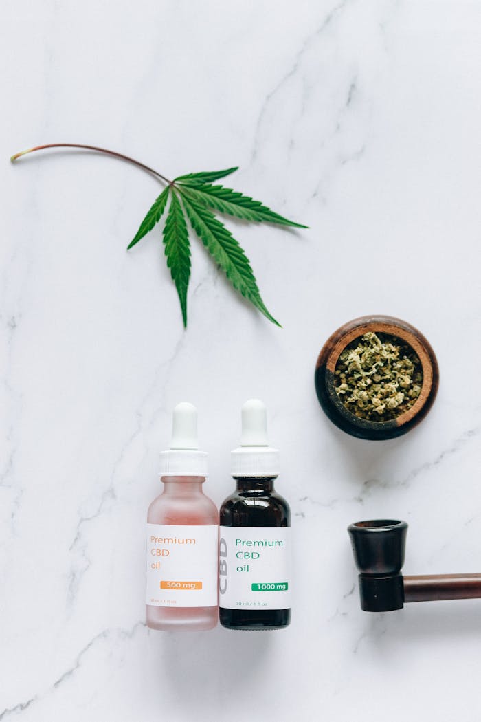 About Flat lay of CBD oil bottles and hemp leaf, emphasizing natural wellness products.